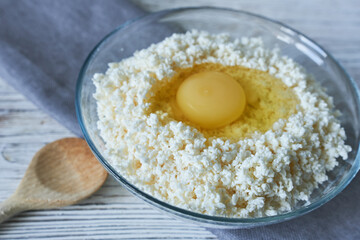 Cottage cheese with egg in a glass bowl on a wooden background