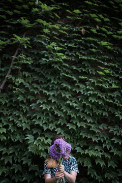 woman holding three purple Alliums