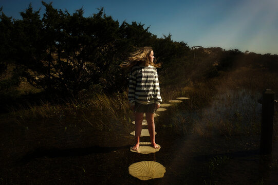 Beautiful teen girl flipping on stone path in flooded field
