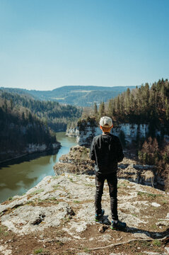 Boy hiking, watching River Doubs, Switzerland, from a cliff viewpoint