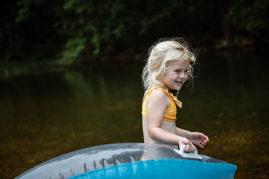 Happy young child floating on river during summer float trip