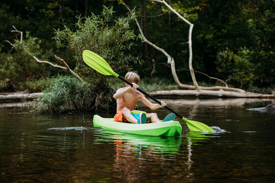 Child kayaking in kid's kayak on river during summer