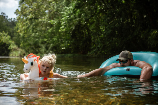 Dad and daughter relaxing in river on hot summer day