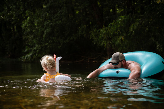 Dad and daughter swimming with inflatables in river