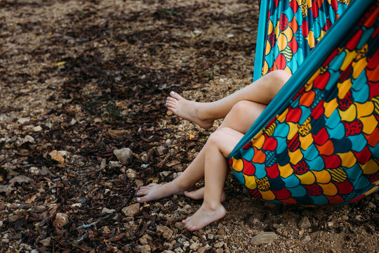 Kids legs hanging out of colorful hammock at camp