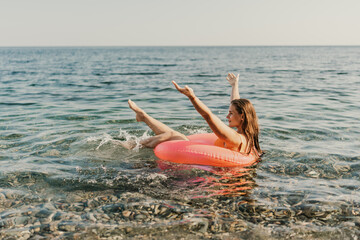 A woman is in the ocean, holding onto a red inflatable ring