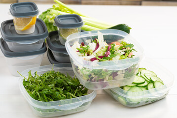 Chopped salad, vegetables and herbs in a plastic container. Storing food for freezing