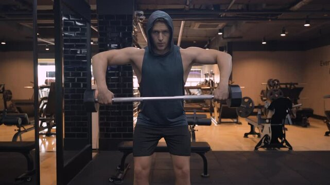 Man Doing Wide Grip Upright Row Exercise in Bent Position for Rear and Mid Delt Muscles Training at Indoor Gym - front view