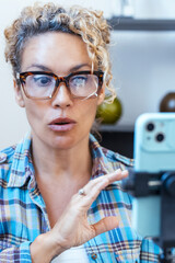 Young adult creative woman live streaming a video for her followers on social media, she is using...