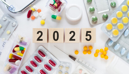 Wooden Blocks Displaying 2025 Surrounded by Various Medications and Pill Organizers