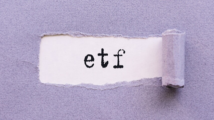 The initials ETF of Exchange Traded Funds on a purple torn paper.