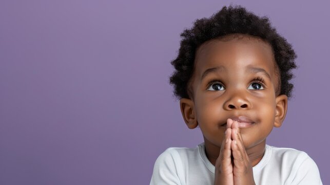 A cute baby with large, hopeful eyes looking upwards, pressing their hands together in a prayer gesture against a purple background. The image evokes innocence and a sense of spirituality.