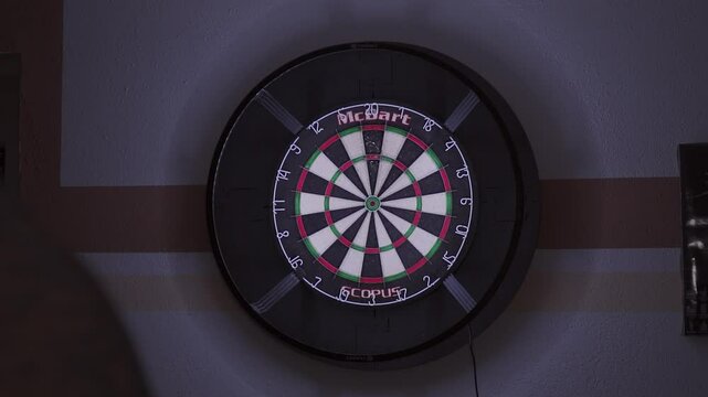 A dartboard with precise hits on the triple 20 in a dimly lit room