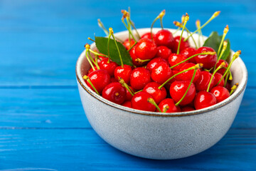 Cherries. Fresh ripe cherries with leaves on a textured wooden background. Fresh sweet organic cherry pile. Berries and fruits. Vegan. Healthy eating. Place for text. Copy space