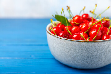 Cherries. Fresh ripe cherries with leaves on a textured wooden background. Fresh sweet organic cherry pile. Berries and fruits. Vegan. Healthy eating. Place for text. Copy space