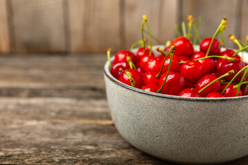 Cherries. Fresh ripe cherries with leaves on a textured wooden background. Fresh sweet organic cherry pile. Berries and fruits. Vegan. Healthy eating. Place for text. Copy space