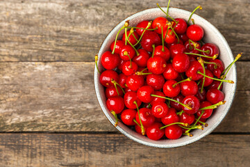Cherries. Fresh ripe cherries with leaves on a textured wooden background. Fresh sweet organic cherry pile. Berries and fruits. Vegan. Healthy eating. Place for text. Copy space