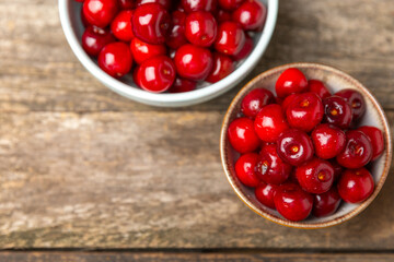Cherries. Fresh ripe cherries with leaves on a textured wooden background. Fresh sweet organic cherry pile. Berries and fruits. Vegan. Healthy eating. Place for text. Copy space