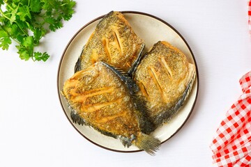 Crispy Fried  gourami fish or fried fish in a white plate on white background, top view food table