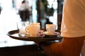 Close-up of a tray with coffees held by a waiter