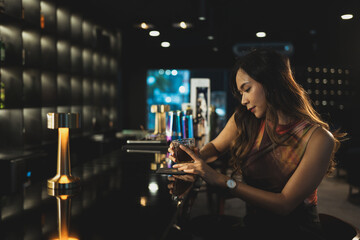 Gorgeous young woman with glass of whiskey sitting at the bar in the luxury interior