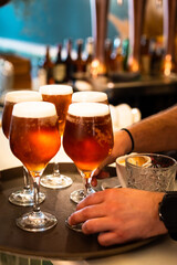 Waiter placing beer glasses on the tray in the restaurant. Vertical