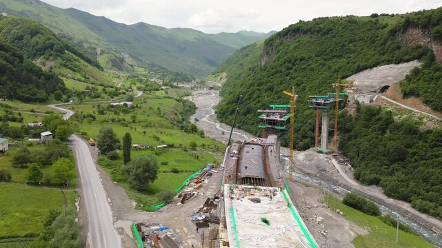Kazbegi, Georgia - 7th july, 2024: aerial view cranes and bridge foundation pillars on construction site of new highway road project built by chinese builders.Avalanche bypass tunnel.Tbillisi - Lars