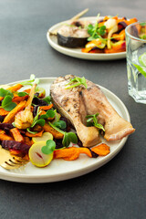 Baked silver carp with roasted carrots, zucchini, beets, and garlic and mint water, perfect for a healthy and delicious breakfast or lunch, plates with food on a dark background