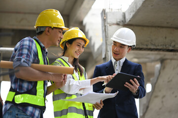Team of engineer and architects in safety hard hats discussing about new project plan at construction site