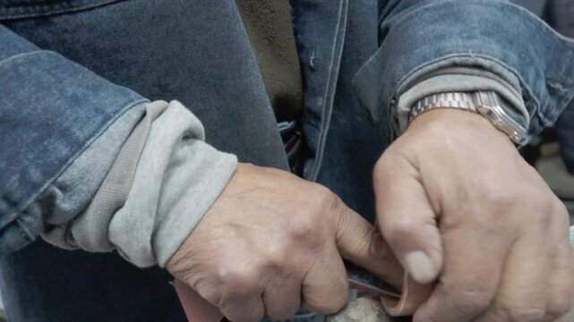 Plumbers sanding copper couplings in slow motion