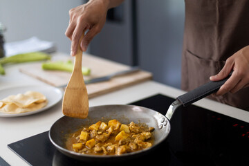 Close-up of chef cooking traditional Indian curry in a frying pan