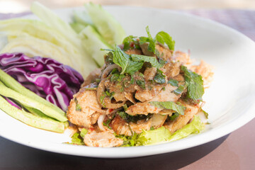 Spicy grilled pork salad (Moo Yang Nam Tok) on white plate. Traditional Thai food recipe.