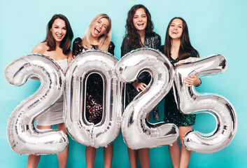 Four Beautiful women celebrating New Year. Happy gorgeous female in stylish sexy party dresses...