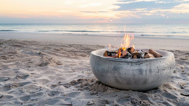 Concrete fire pit with burnt embers on sandy beach