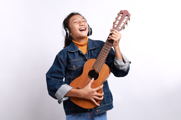 Naklejka premium Happy casual style little girl playing guitalele or small guitar and singing isolated on white background