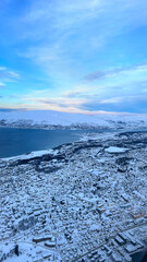 Top view of a nordic city covered in snow with a blue sky