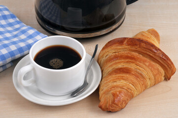 Croissant au beurre traditionnel français avec une tasse de café.