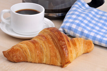 Croissant au beurre traditionnel français avec une tasse de café.