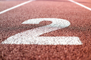 Numer dwa. Bieżnia lekkoatletyczna na stadionie. Zawody sportowe, olimpiada. © Blaszko