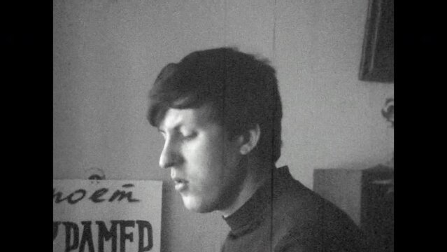 Black white film, focused man singing rehearsing, close up. Serious talent guy practicing music song, look in camera. Passionate, inspired singer. Enjoys male face indoor. Vintage archive. Retro 1960s