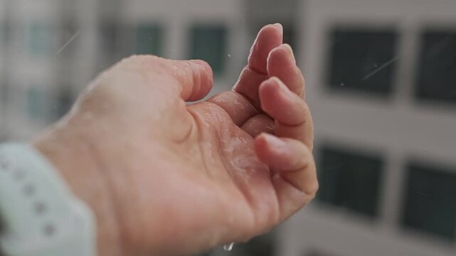 Closeup of Lady Hand with Rain Water Drops reaches to wet Skin Surface Under Falling raindrop. Enjoying Freshness at Summer or Spring Storm. Abstract Slow Motion shoot