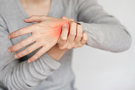 Close-up of a person's hand experiencing wrist pain and discomfort, highlighted by a red mark, showcasing a health issue or injury.