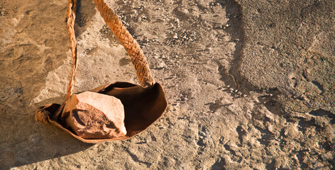 An antique leather sling lies on the ground