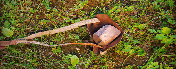 An antique leather sling lies on the ground
