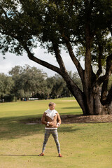 Naklejka premium A blonde man in a brown jacket and plaid pants walks across a green park in Miami.