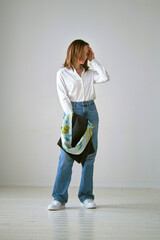 woman looks effortlessly chic in a white blouse and blue jeans, with a black blazer and vibrant...