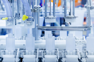 robot arm moving plastic bottle to conveyor belt of auto capping and labeling machine at cosmetic...