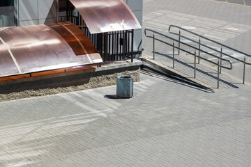 In front of a building with a copper roof, there is a trash can placed