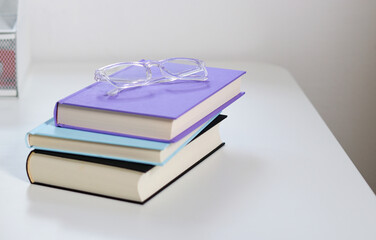 Close up mock up books stack and glasses on top on white table with copy space