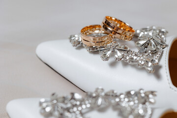 A pair of wedding rings are on a pair of white shoes. The rings are gold and silver, and they are placed on top of the shoes
